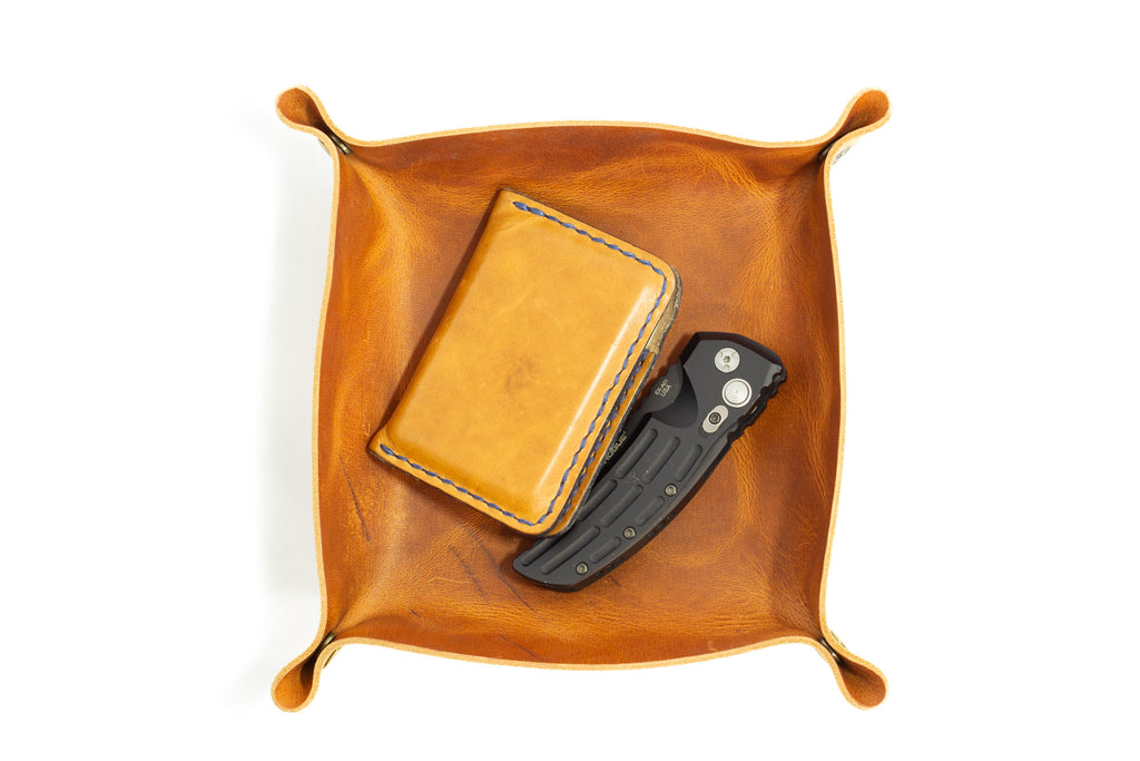 Brown leather tray with a wallet and knife on a white background
