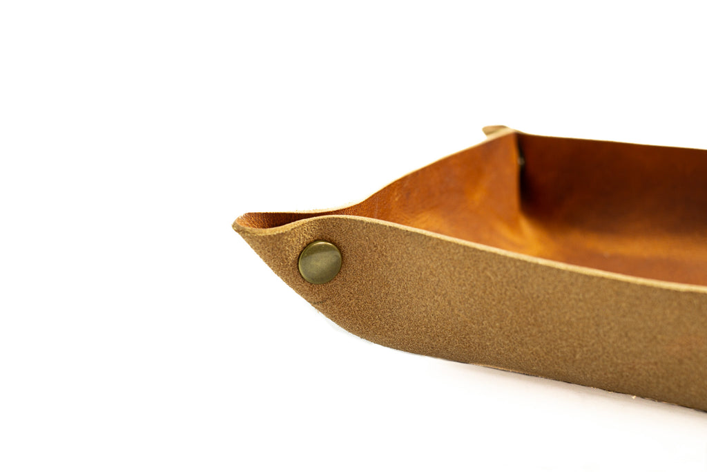 brown full grain leather catchall tray with solid brass snap on white background.