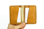 Hand holding a tan leather wallet with card slots on a white background